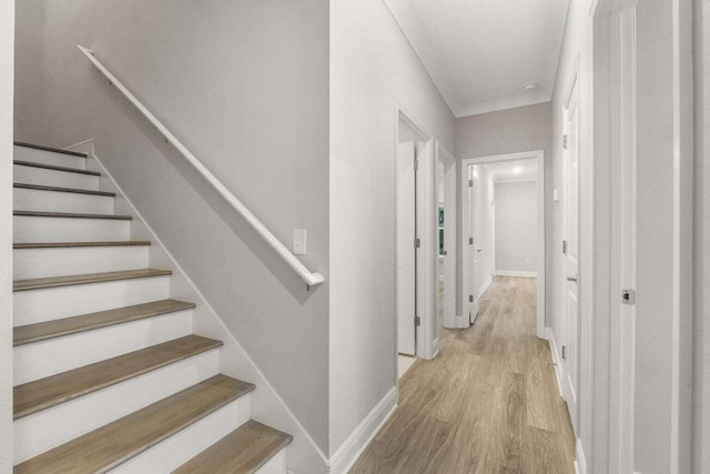 hallway with crown molding and light wood-type flooring