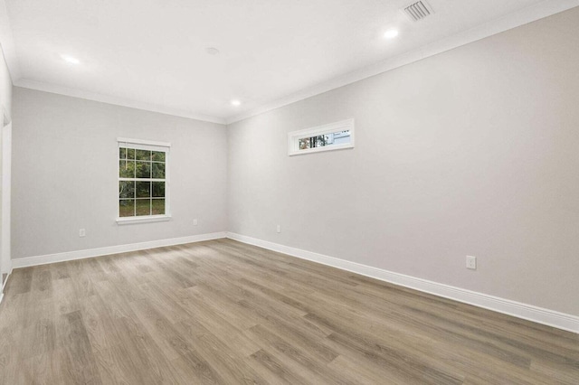 empty room with crown molding and light hardwood / wood-style flooring