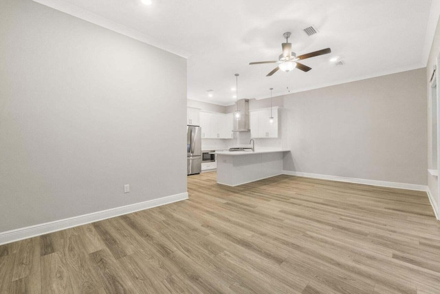 unfurnished living room featuring ceiling fan, ornamental molding, sink, and light wood-type flooring