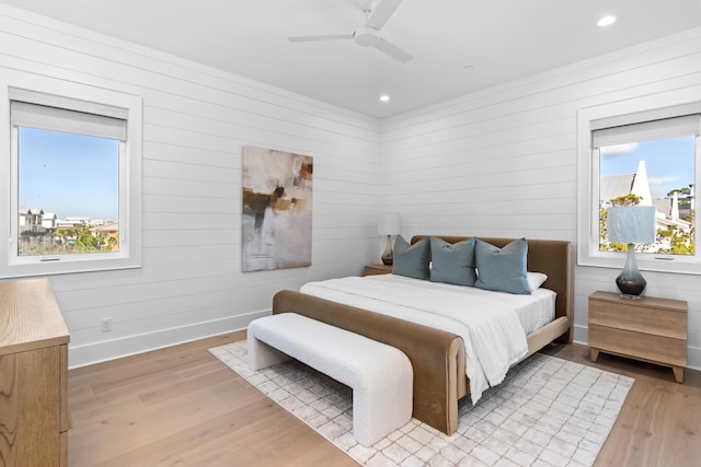 bedroom featuring ceiling fan, light hardwood / wood-style flooring, and multiple windows