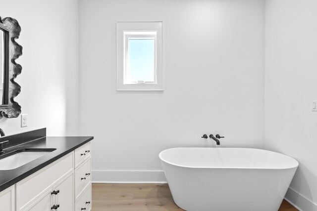 5050 W County Highway 30a, Santa Rosa Beach, FL 32459 - bathroom with baseboards, vanity, a freestanding tub, and wood finished floors