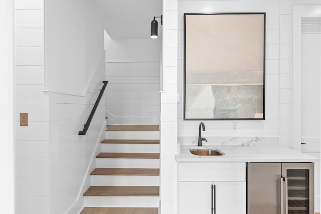 stairs with hardwood / wood-style floors, wet bar, and beverage cooler