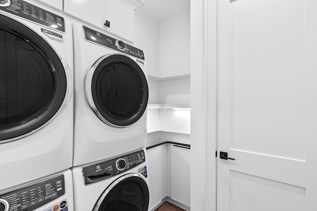 washroom with stacked washer / drying machine and cabinets