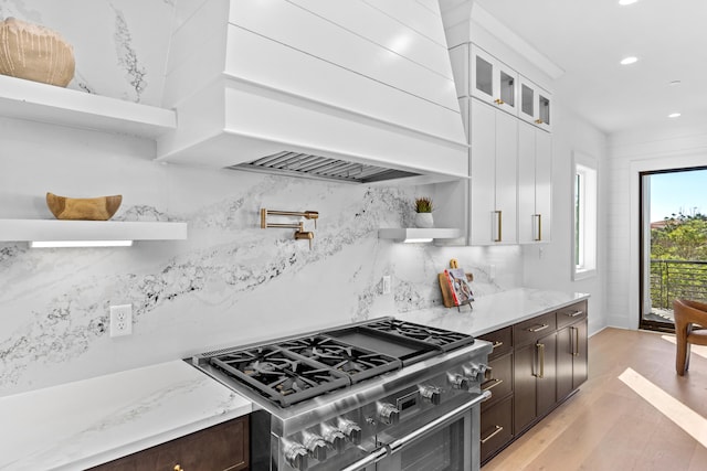 kitchen with dark brown cabinetry, custom range hood, white cabinets, and range with two ovens