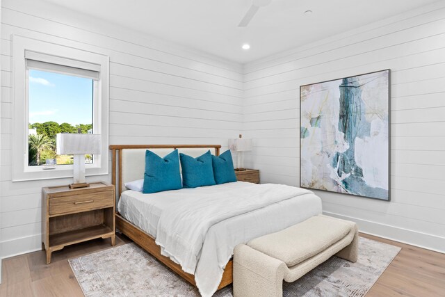 bedroom with hardwood / wood-style floors, ceiling fan, and wooden walls