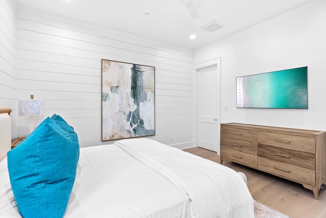 bedroom featuring ceiling fan, wooden walls, and hardwood / wood-style flooring