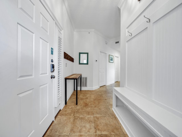 mudroom with crown molding and a textured ceiling