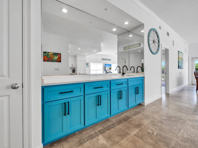 interior space with sink, crown molding, and blue cabinetry