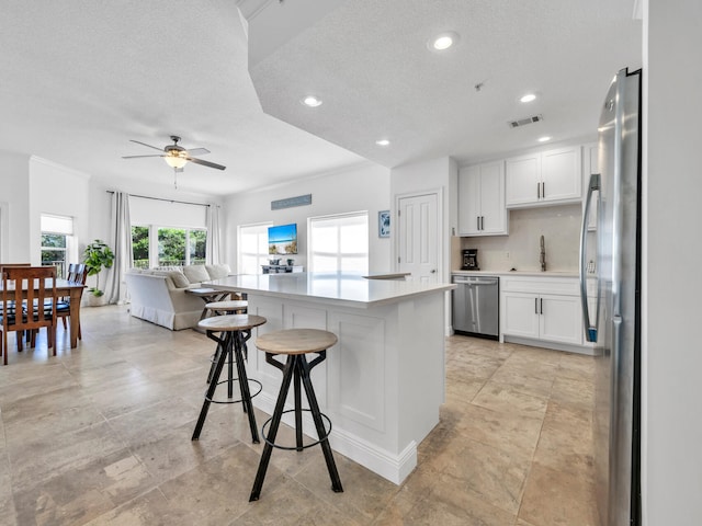 kitchen featuring sink, stainless steel appliances, white cabinets, and a kitchen bar