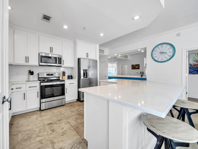 kitchen with stainless steel appliances, a kitchen breakfast bar, and white cabinets