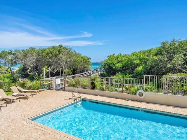 view of pool with a water view and a patio area