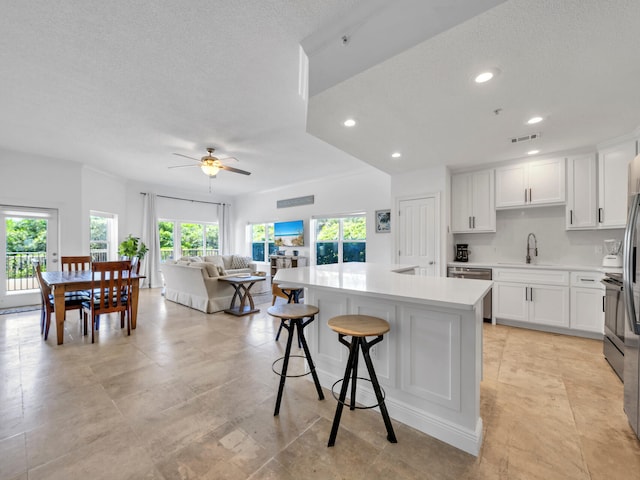 kitchen with sink, dishwasher, white cabinetry, a kitchen breakfast bar, and a center island