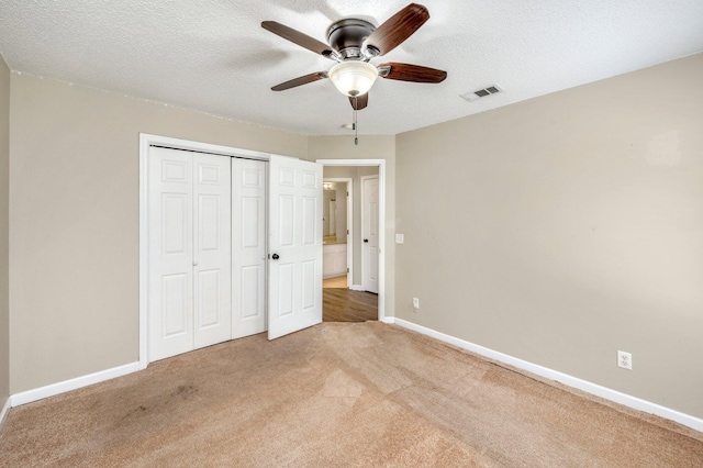 unfurnished bedroom with carpet, ceiling fan, a textured ceiling, and a closet