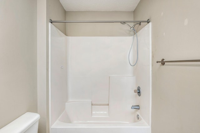 bathroom featuring toilet, a textured ceiling, and bathtub / shower combination