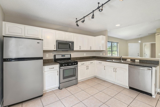 kitchen featuring appliances with stainless steel finishes, a textured ceiling, vaulted ceiling, sink, and white cabinets