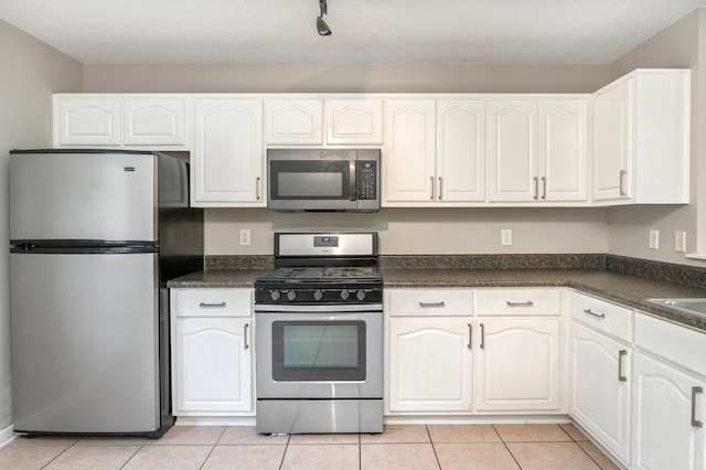 kitchen with white cabinets, light tile patterned flooring, a textured ceiling, and appliances with stainless steel finishes