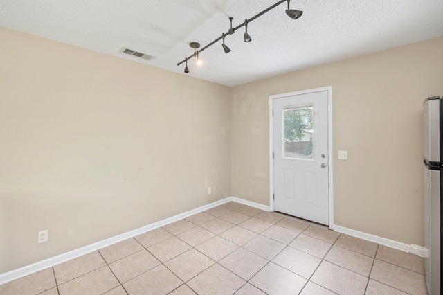 interior space featuring light tile patterned flooring and a textured ceiling