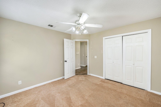 unfurnished bedroom with light carpet, a textured ceiling, a closet, and ceiling fan