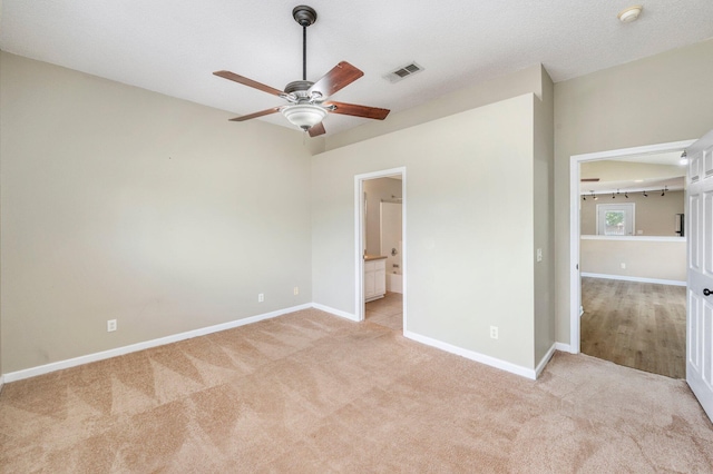 unfurnished bedroom with ceiling fan, light colored carpet, and ensuite bath