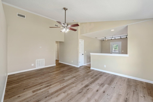 unfurnished living room featuring ceiling fan, rail lighting, light hardwood / wood-style flooring, a textured ceiling, and lofted ceiling