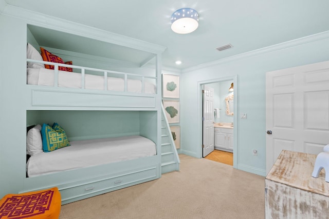 carpeted bedroom with ensuite bathroom and ornamental molding