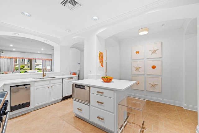 kitchen with sink, light tile patterned floors, a kitchen island, stainless steel dishwasher, and white cabinets