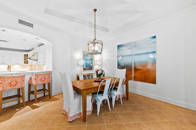 tiled dining space with a raised ceiling, crown molding, sink, and a chandelier