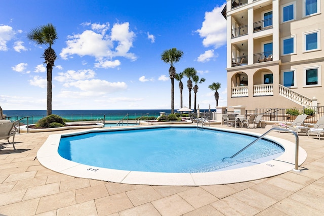 view of swimming pool with a water view and a patio area