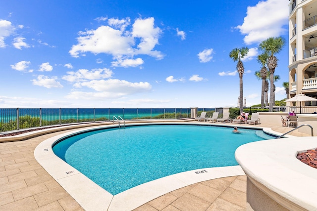 view of pool with a patio and a water view