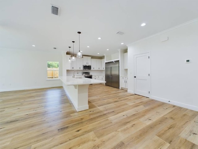 kitchen featuring white cabinets, pendant lighting, ornamental molding, stainless steel appliances, and light wood-type flooring