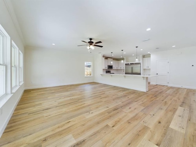 unfurnished living room with light hardwood / wood-style flooring, ceiling fan, ornamental molding, and sink