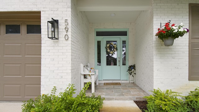 property entrance with brick siding and an attached garage