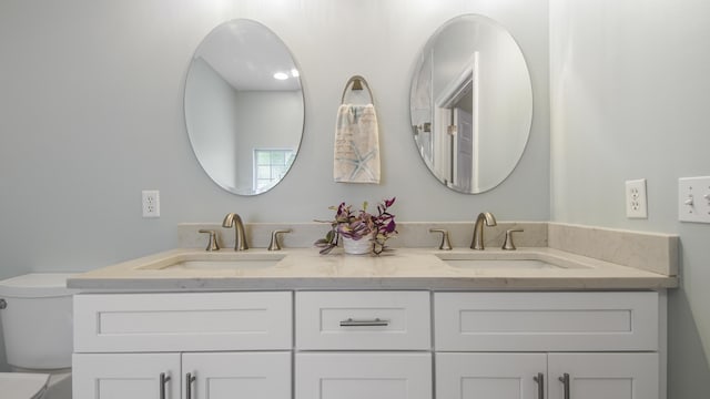 bathroom with double vanity, a sink, and toilet