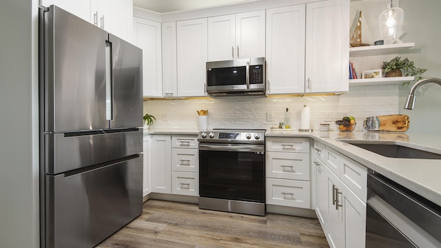 kitchen featuring sink, white cabinetry, hanging light fixtures, and stainless steel appliances