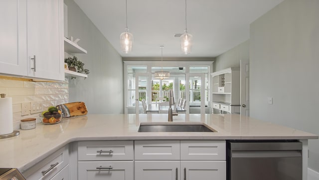 kitchen featuring decorative light fixtures, white cabinetry, sink, backsplash, and light stone counters