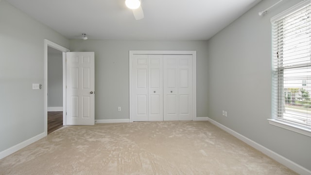 unfurnished bedroom featuring a closet, ceiling fan, and light colored carpet