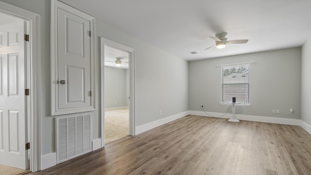 empty room featuring light wood-style flooring, visible vents, ceiling fan, and baseboards