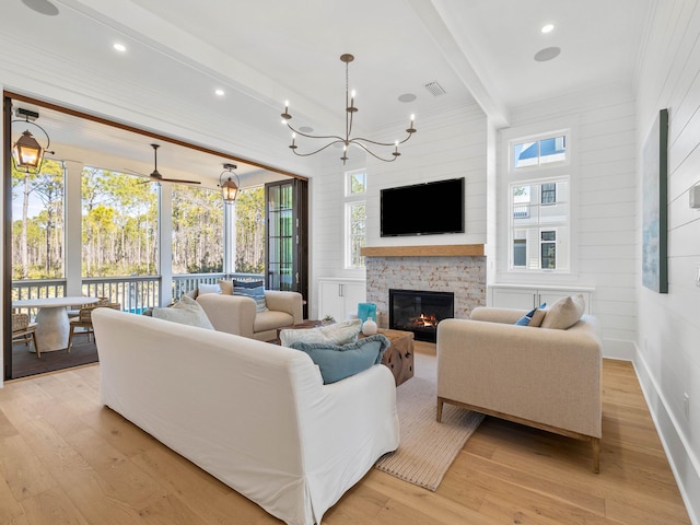 living room featuring ceiling fan with notable chandelier, beam ceiling, a fireplace, and light hardwood / wood-style flooring