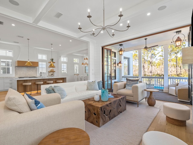 living room featuring beamed ceiling, light wood-type flooring, and crown molding