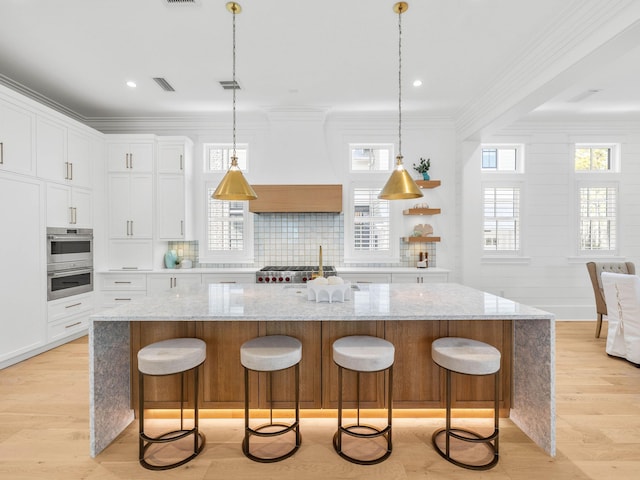 kitchen with pendant lighting, a center island, light stone counters, and white cabinetry