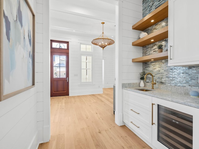 interior space featuring white cabinets, light stone countertops, sink, and beverage cooler