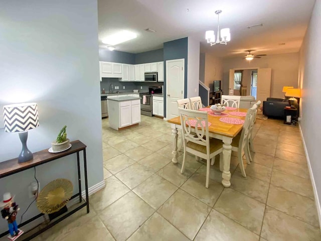 dining space featuring ceiling fan with notable chandelier, sink, and light tile patterned floors