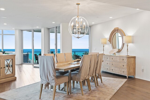 dining space with an inviting chandelier, a water view, and wood-type flooring