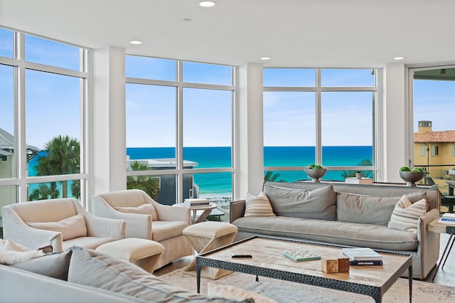 living room with a wall of windows, a water view, and a wealth of natural light