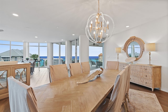 dining room with a water view, parquet flooring, expansive windows, and an inviting chandelier