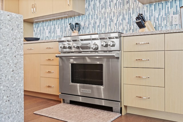 kitchen featuring high end stainless steel range oven, light brown cabinetry, and dark hardwood / wood-style floors