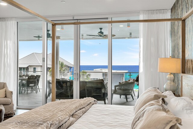 bedroom with floor to ceiling windows, a water view, and multiple windows