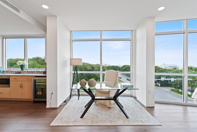 sitting room with a wealth of natural light, expansive windows, beverage cooler, and hardwood / wood-style floors