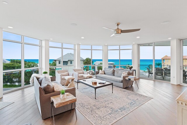 living room with floor to ceiling windows, a water view, and hardwood / wood-style floors