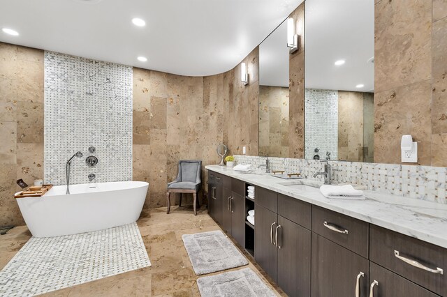 bathroom featuring dual vanity, tile walls, a bath, and tile patterned flooring